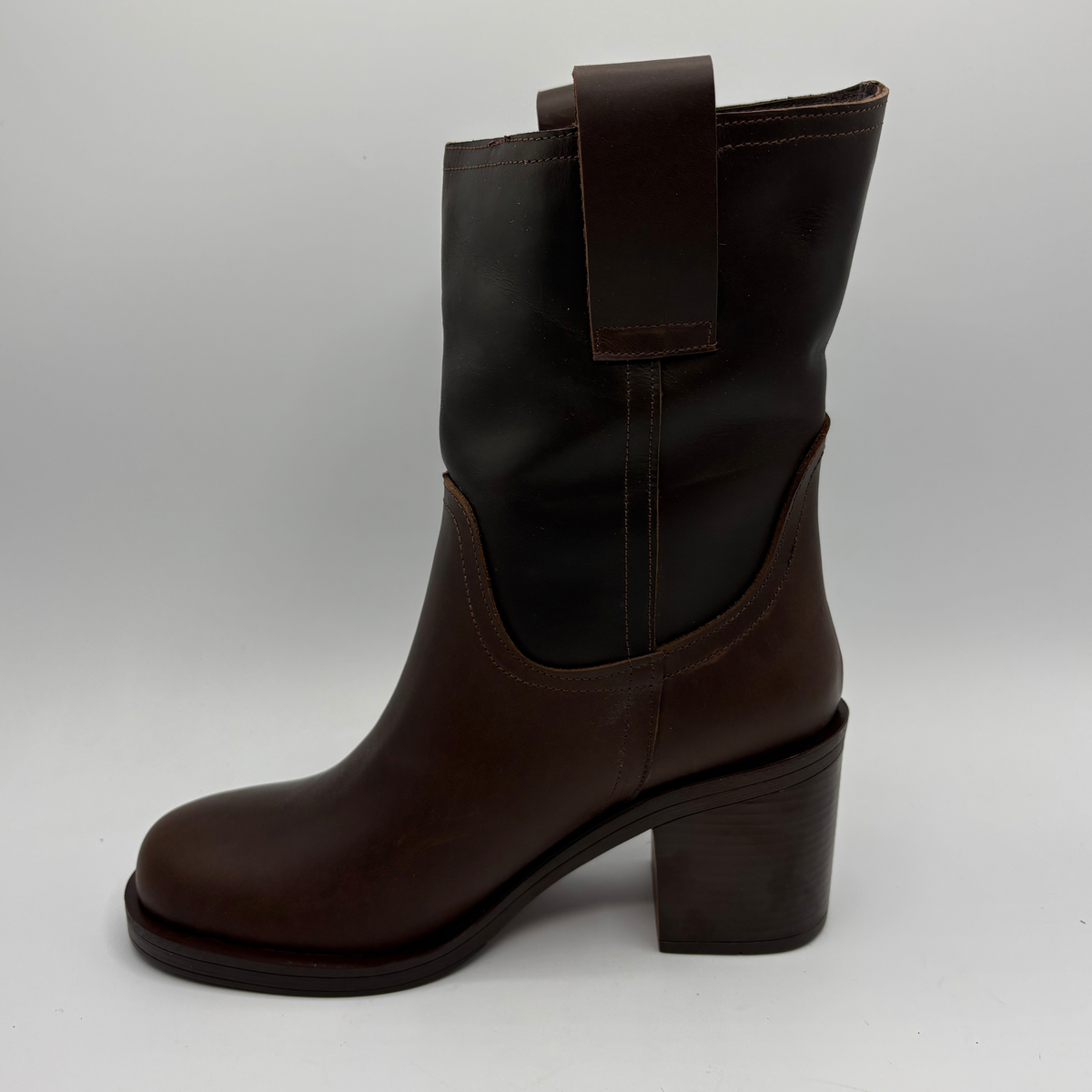 Left facing view of a brown leather short boot with a stacked heel and gold button accent