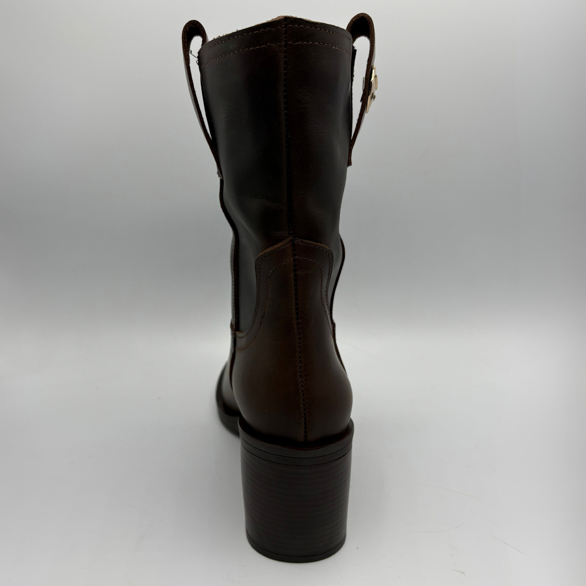 Back view of a brown leather short boot with a stacked heel and gold button accent
