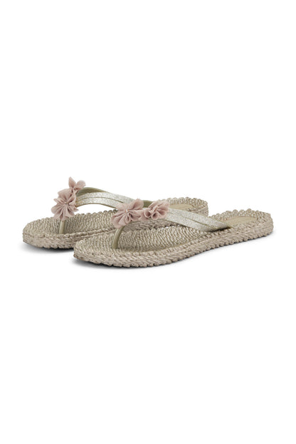 Pair of light-colored sandals with floral straps on a white background
