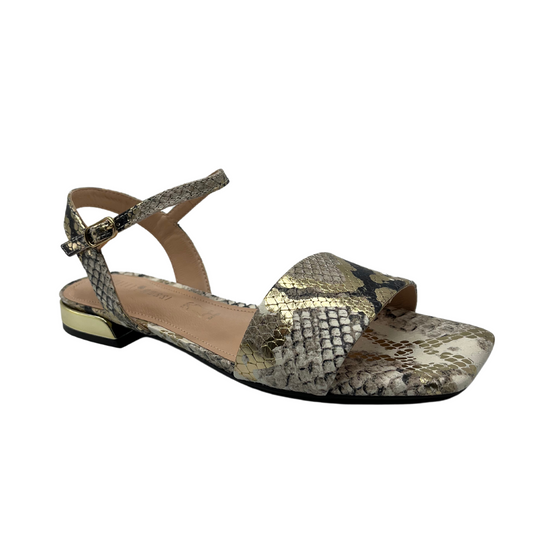 Angled view of flat snake skin design leather sandal with square toe and gold detail on heel