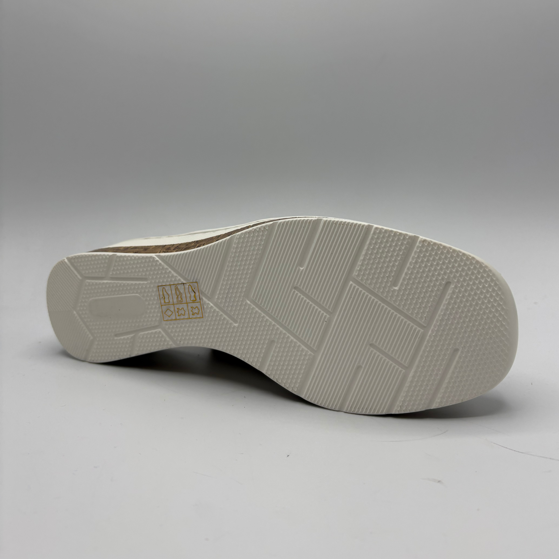 Close-up of a white shoe sole with tread pattern on a gray background