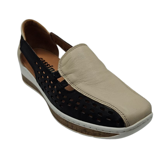 45 degree angled view of beige and black leather slip on shoe with elastic side straps and a synthetic sole