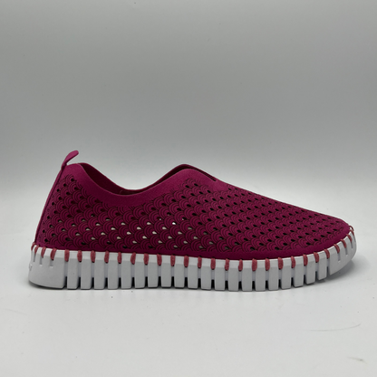 Right facing view of cerise slip on shoe with an intricate laser cut upper and white rubber outsole.