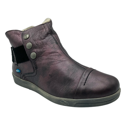 45 degree angled view of leather ankle bootie with cap toe and wrap around strap. Grey rubber outsole and 3 grey button detail on upper