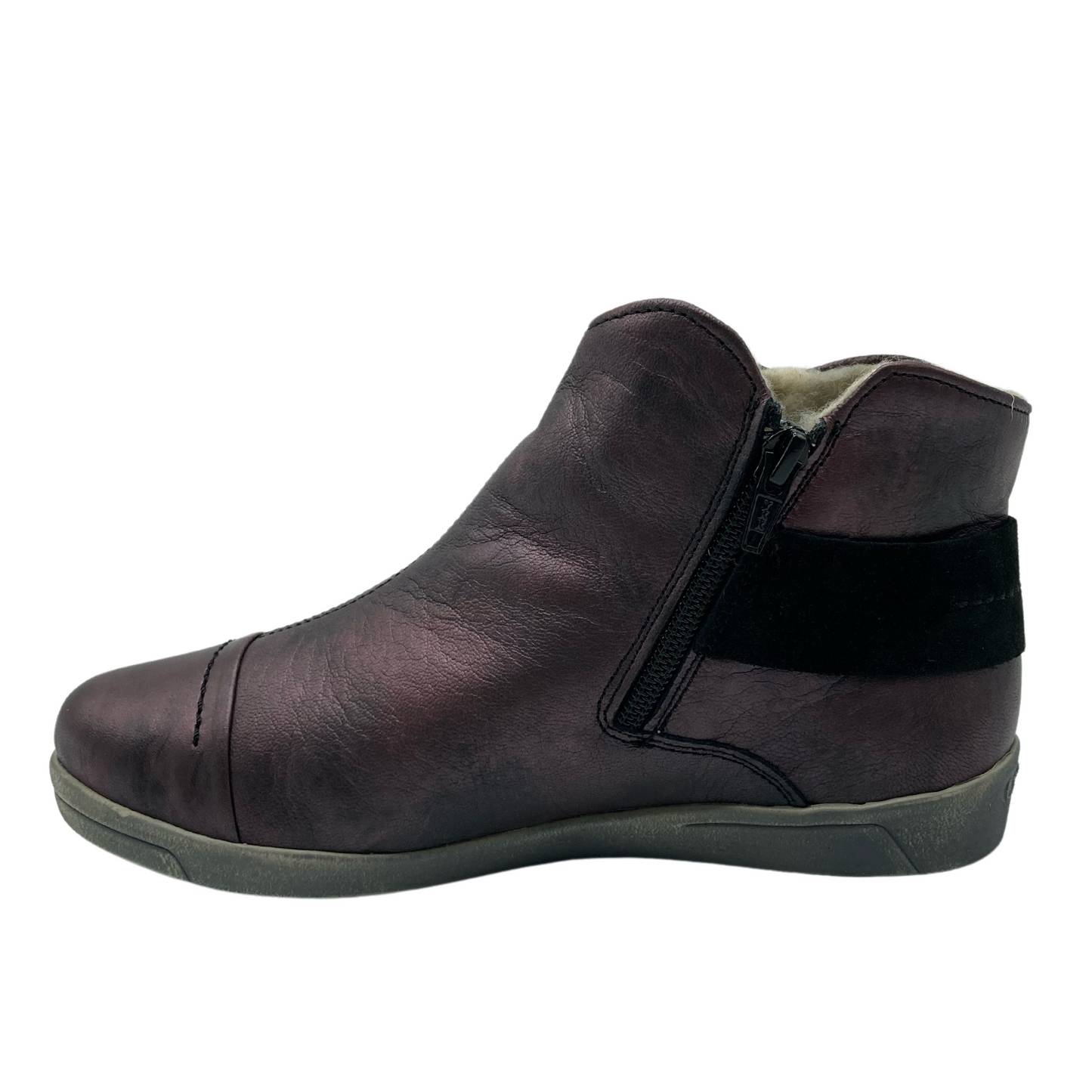 Left facing view of leather short boot with wrap around strap, grey rubber outsole and side zipper closure