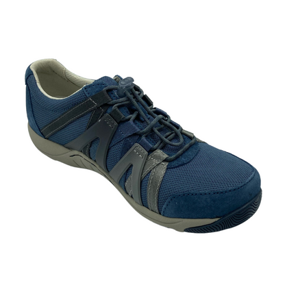A blue sneaker viewed from a 45 degree angle. The shoe has navy cord-like laces, a mesh top, suede detailing, and an Ombre zig-zagged side pattern.
