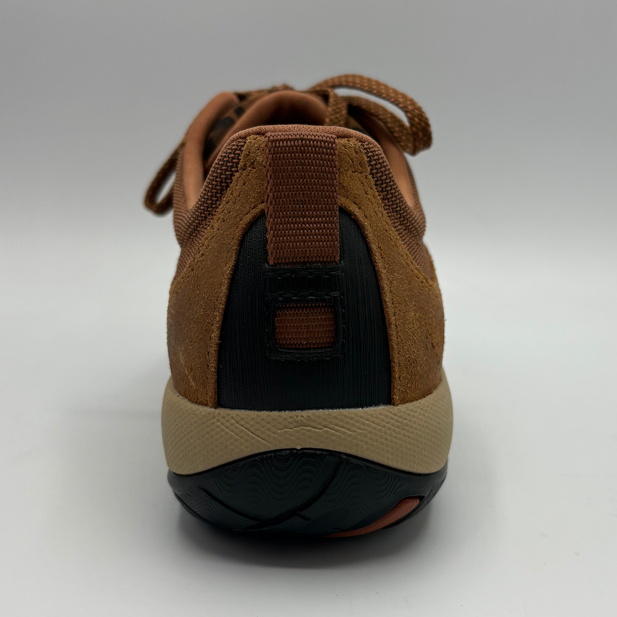 A brown low-top sneaker with a leopard-print pattern panel, black toe cap and outsole, and a beige midsole, shown from the back on a white background.