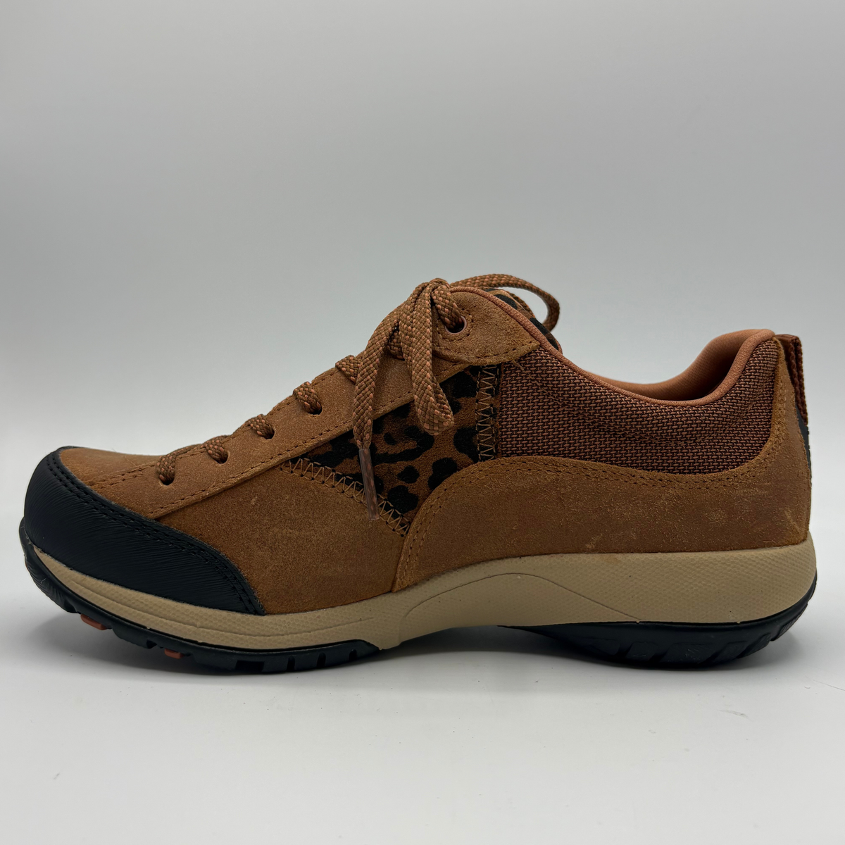 A brown low-top sneaker with a leopard-print pattern panel, black toe cap and outsole, and a beige midsole, shown from the side on a white background.