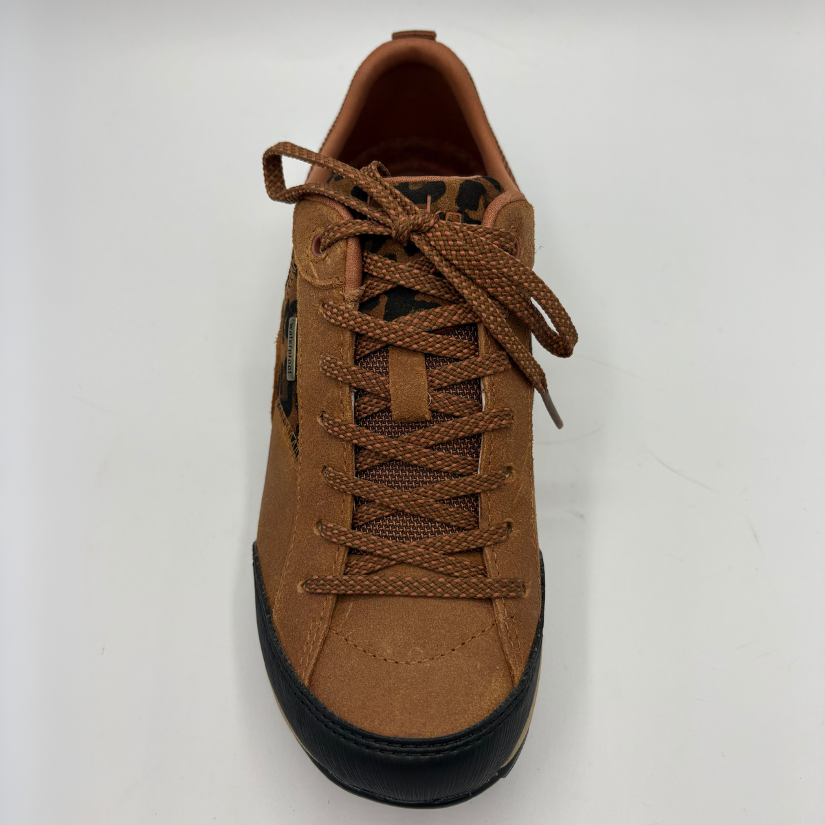 A brown low-top sneaker with a leopard-print pattern panel, black toe cap and outsole, and a beige midsole, shown from the top on a white background.