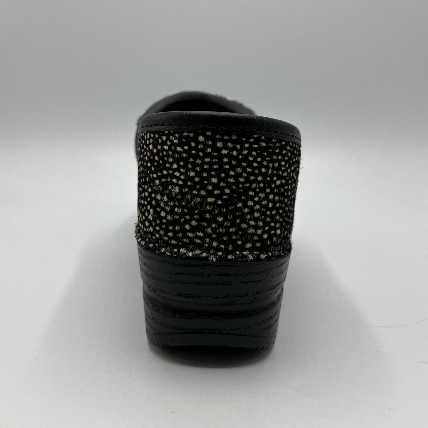 Black slip-on shoe with textured sole on a light gray background