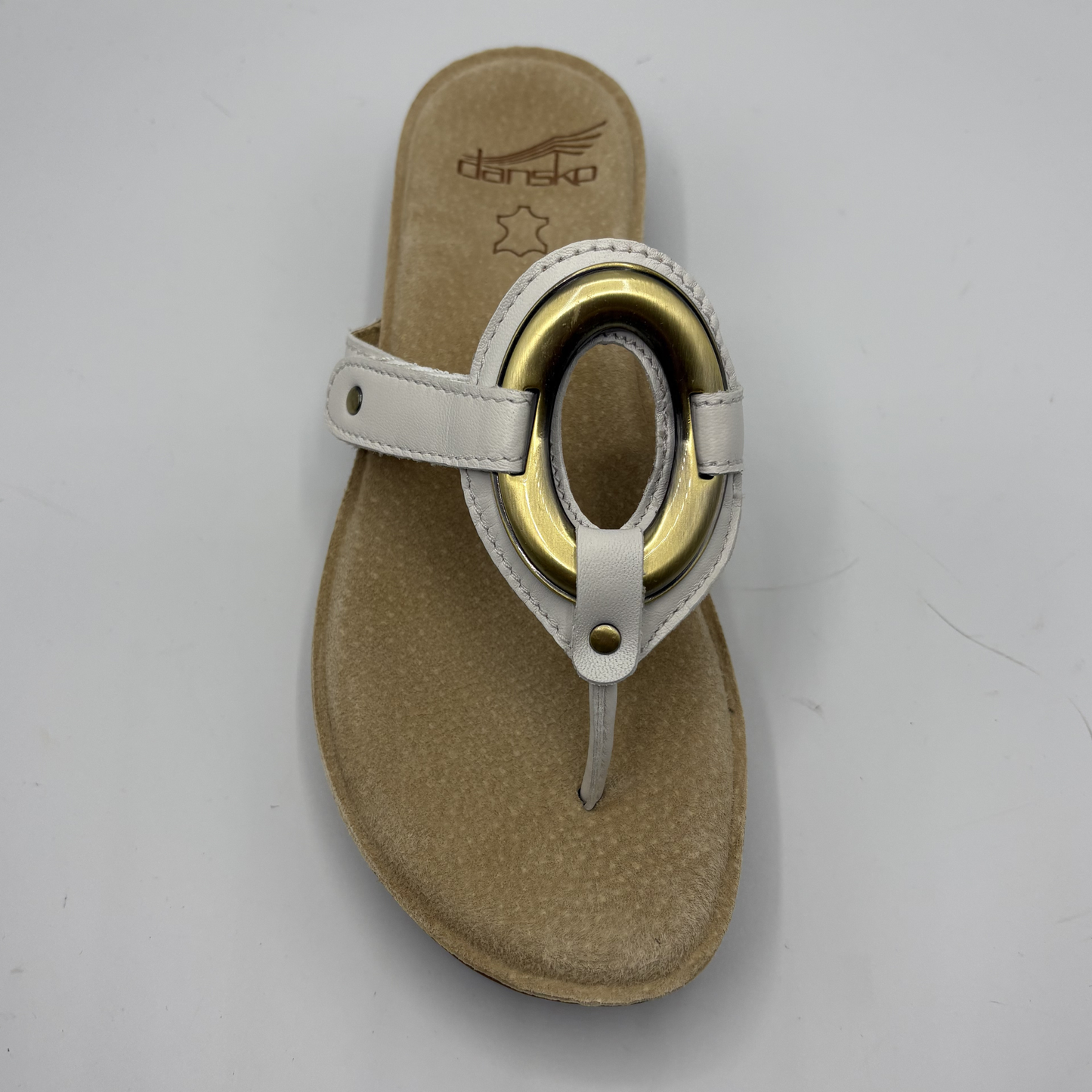 Beige sandal with gold ring on a white background
