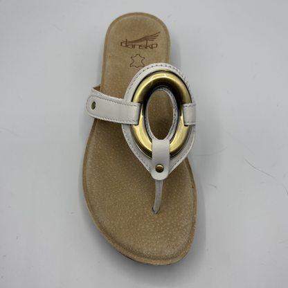 Beige sandal with gold ring on a white background