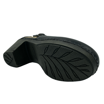 View of the bottom of a leather clog with grey sole with leaf design in the tread