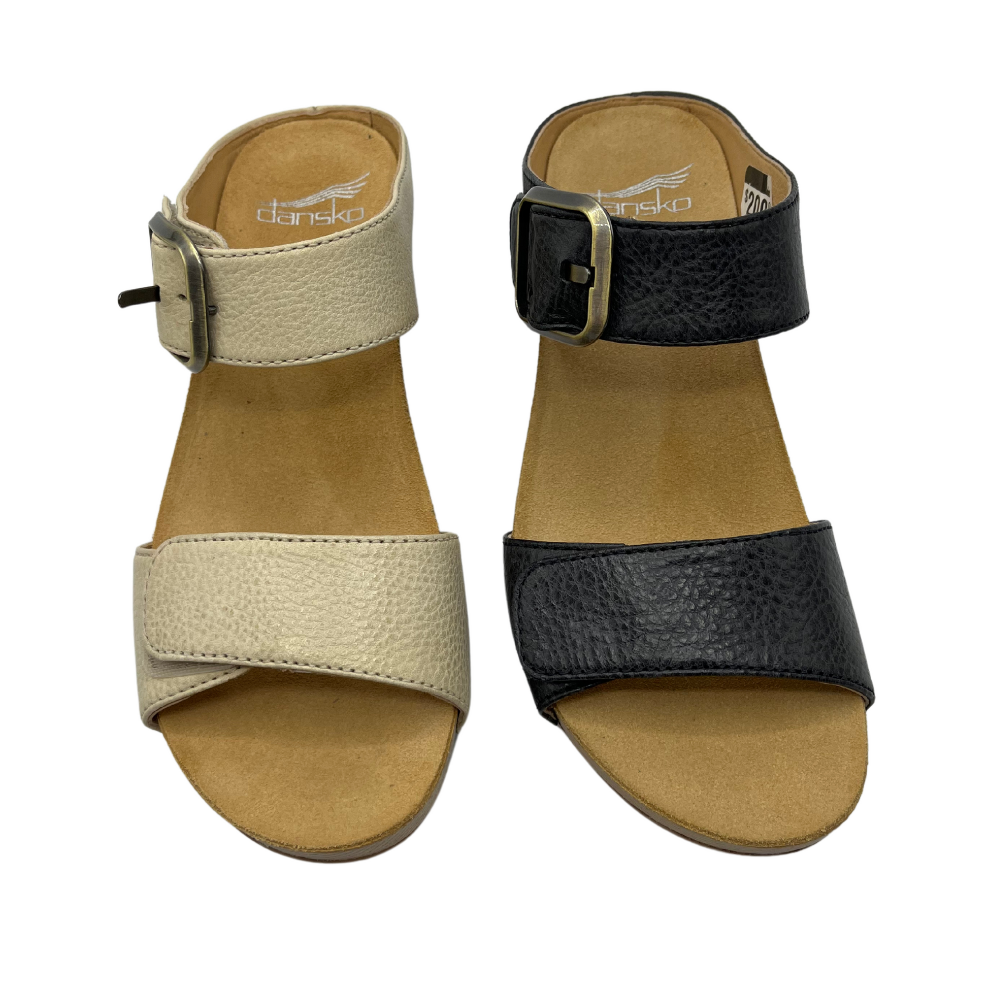 Top view of two leather strapped sandals in a slip on style. The left one is beige and the right one is black. Both have a tan lining and buckle strap.