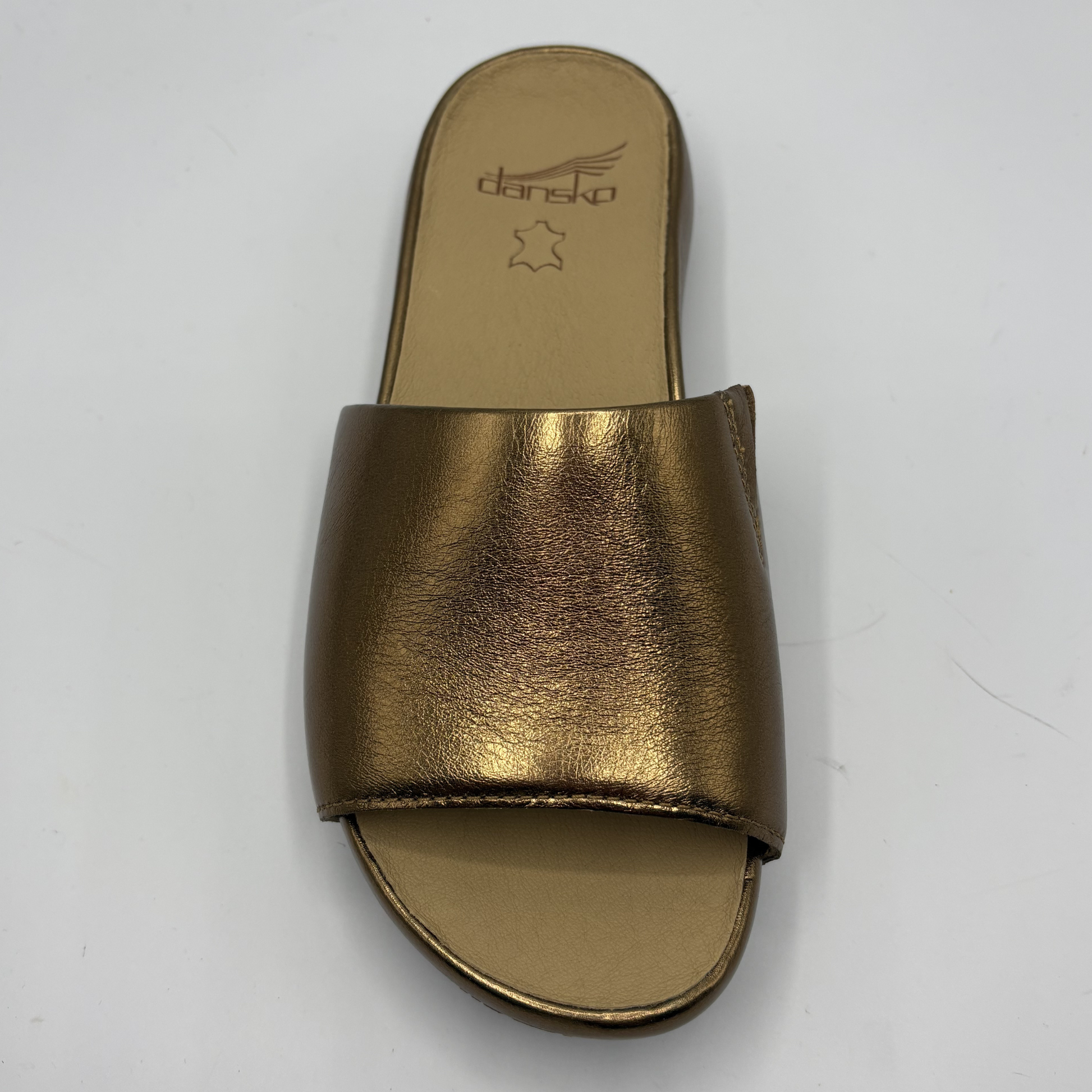 Gold sandal with 'Dansko' branding on a white background
