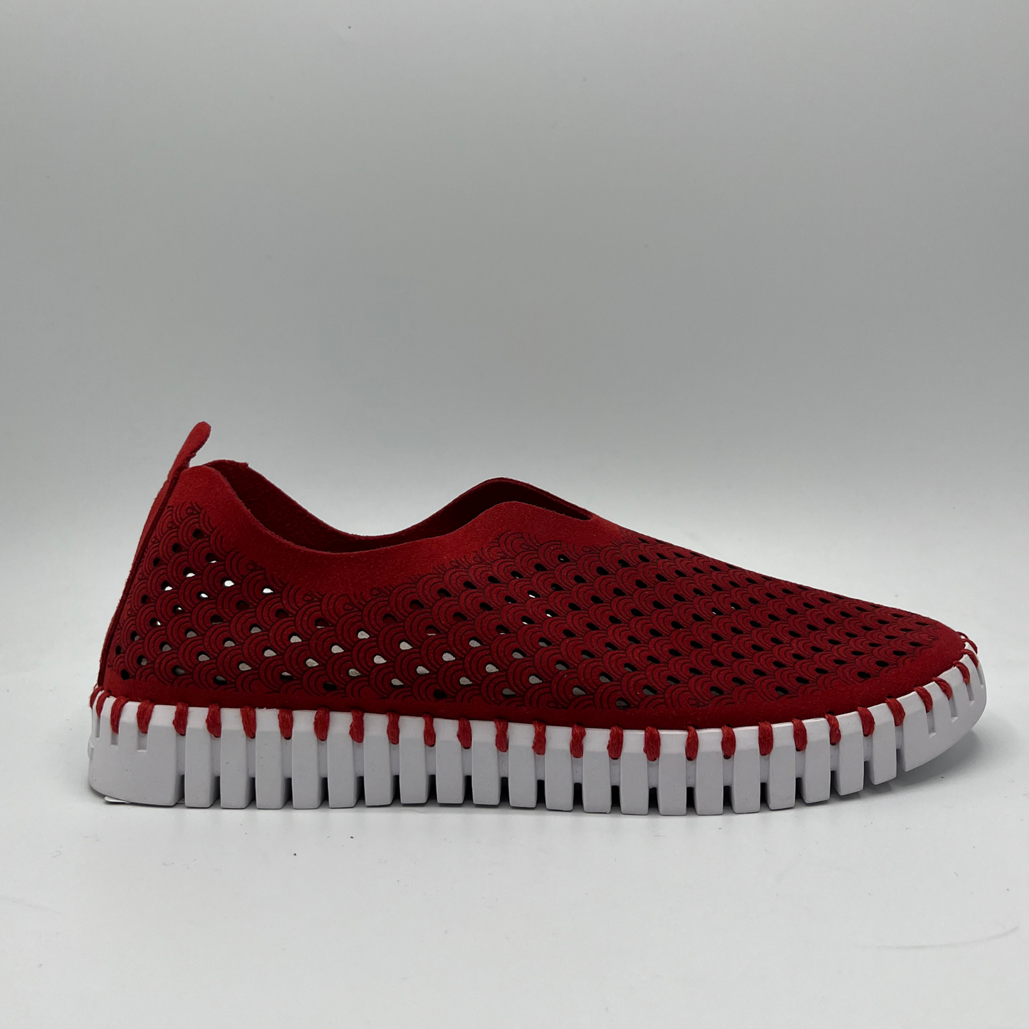 Right facing view of deep red slip on shoe with an intricate laser cut upper and white rubber outsole.