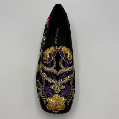 A single black slip-on loafer-style shoe with ornate floral embroidery in gold, purple, red, and green on a plain light background.