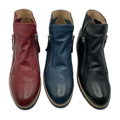View of 3 short boots side by side. On the left is the red leather boot, middle is the navy coloured leather boot and on the right is the black leather boot