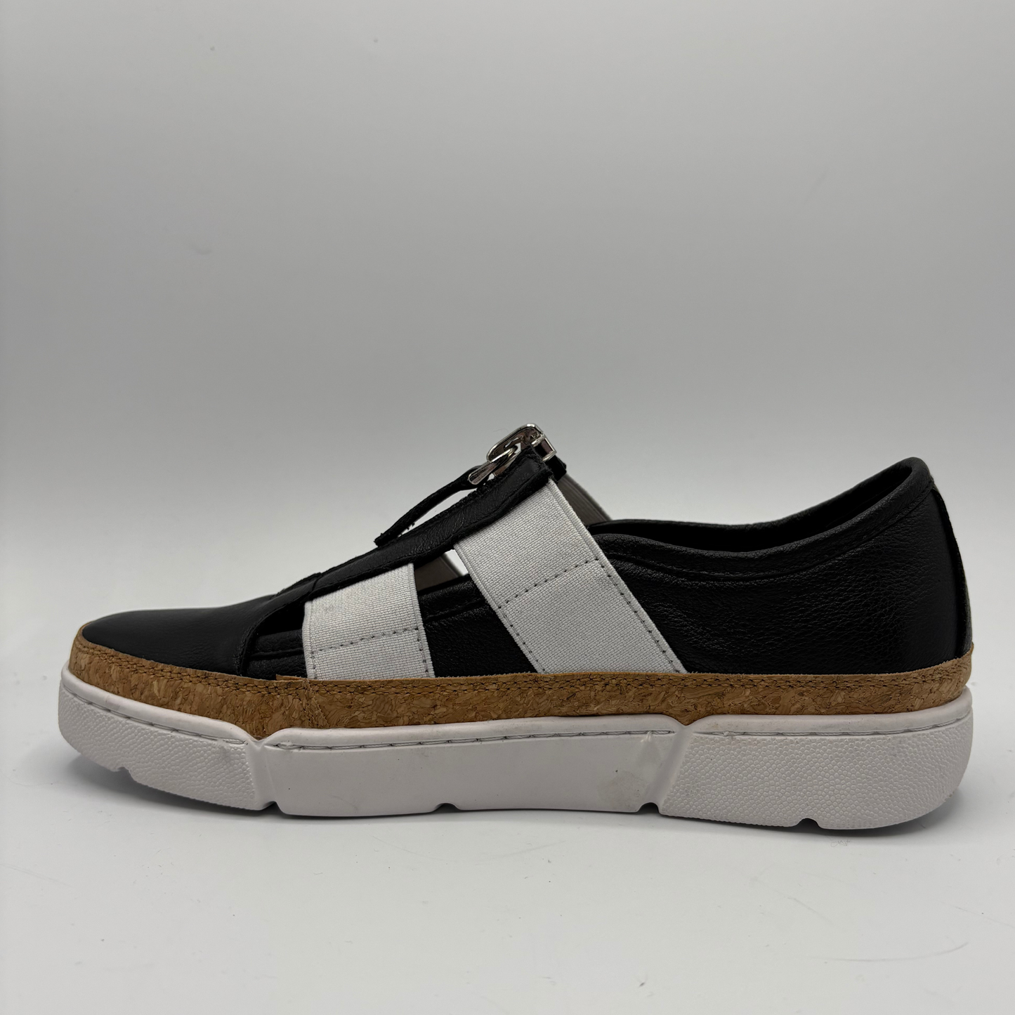 Black and white sneaker with a brown sole on a gray background