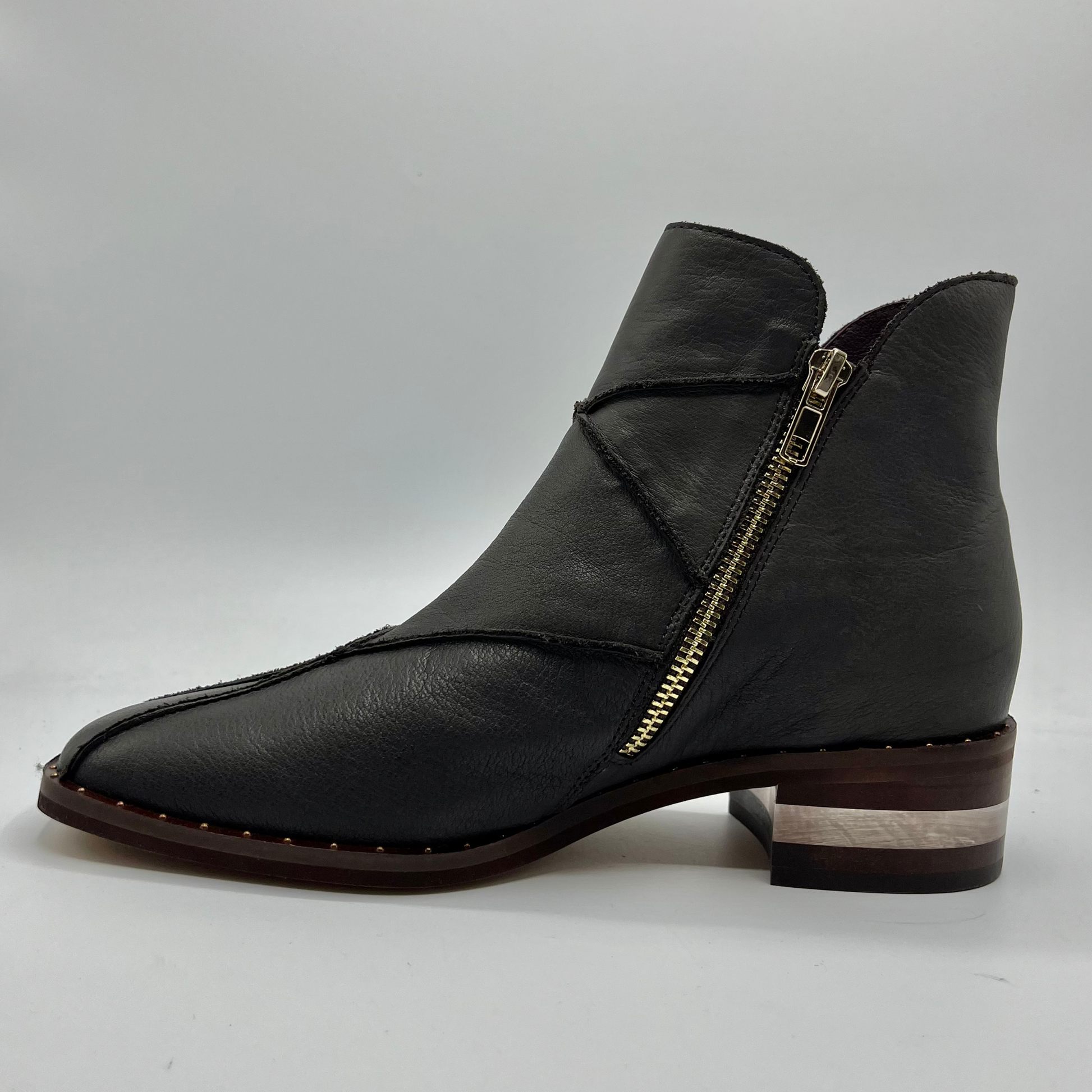 Left facing view of a leather ankle boot with a gold zipper