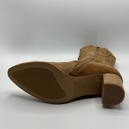 A tan suede boot shown from the side, displaying its pointed toe, textured outsole, side zipper, and stacked block heel against a light gray background.