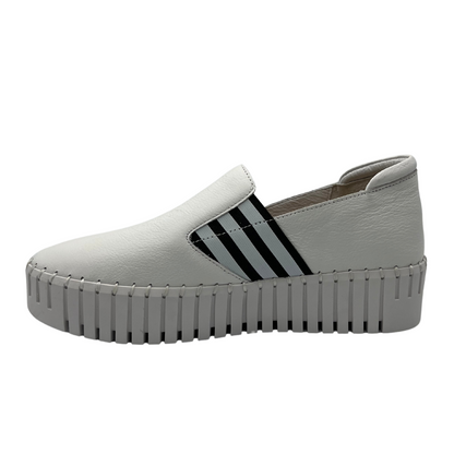 Left facing view of white leather slip on shoe with platform sole and elastic side gores