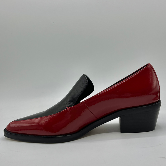 Red patent leather shoe with a black sole on a gray background