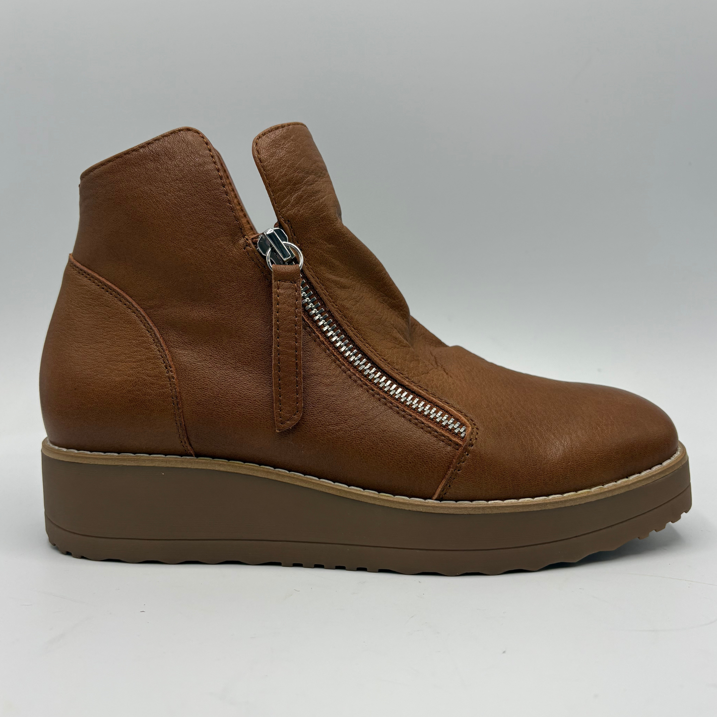 A brown leather ankle boot with a side zipper, a thick brown platform sole, and a light tan welt, shown from a side profile view on a light gray background.