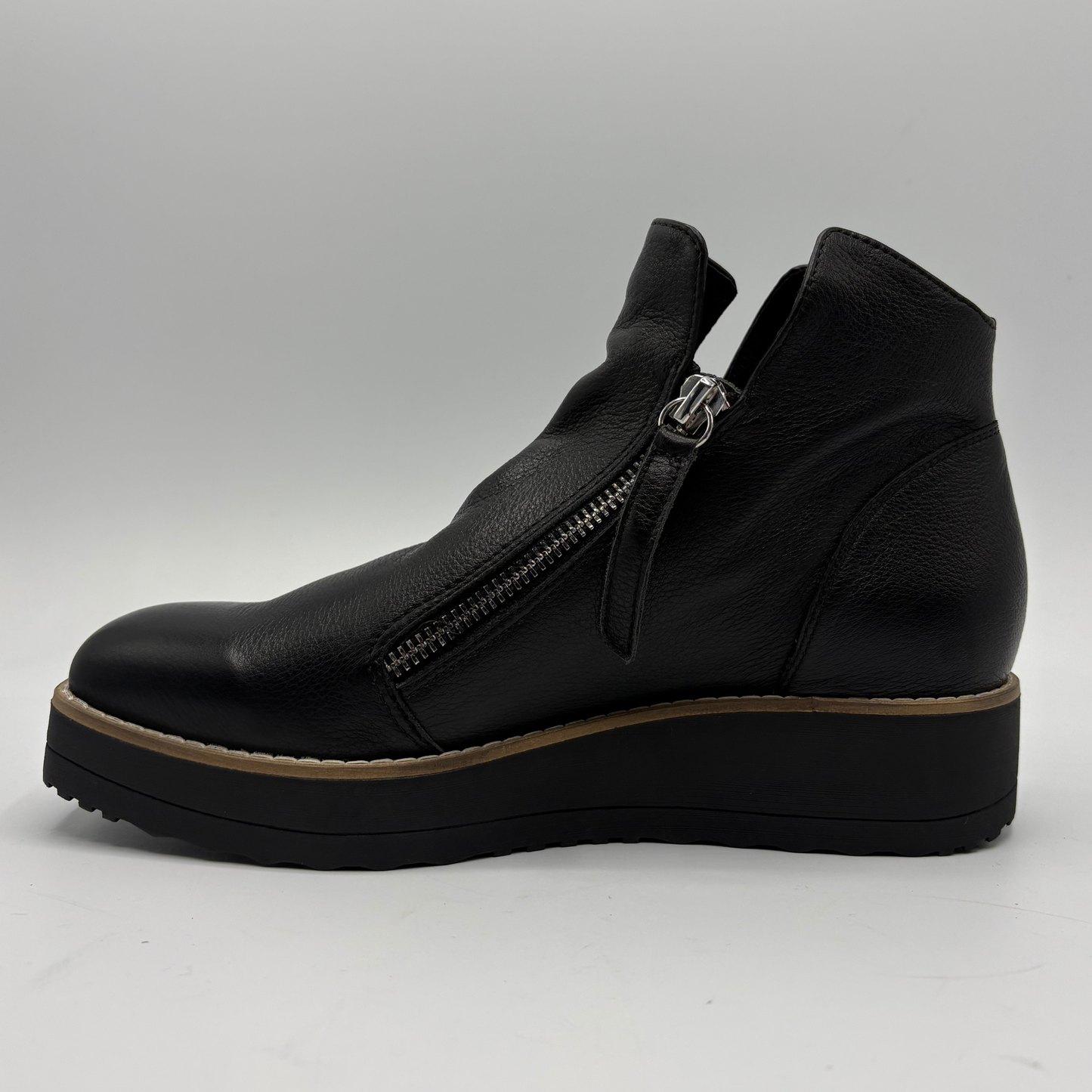 A black leather ankle boot with a side zipper, a chunky black platform sole, and a tan midsole stripe, shown from a side profile view against a light gray background.