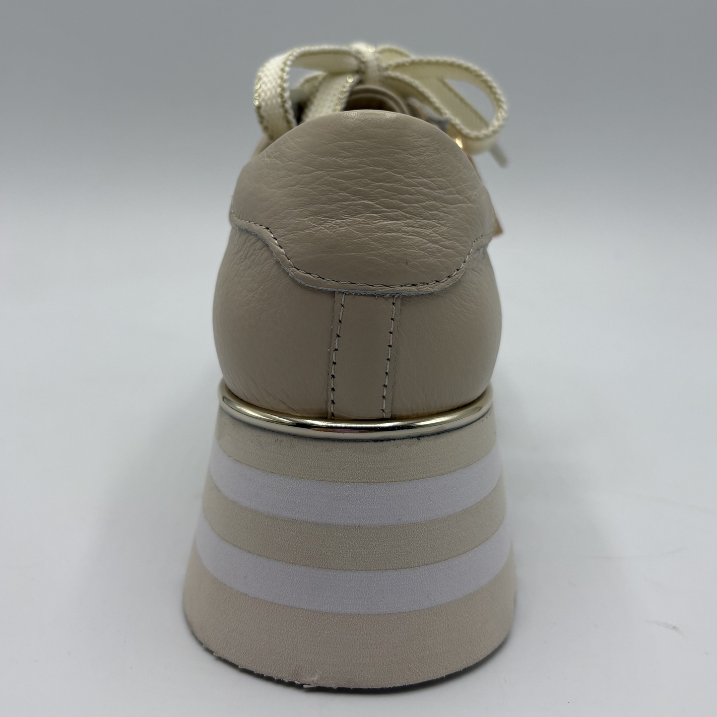 Beige shoe with white stripes on a gray background