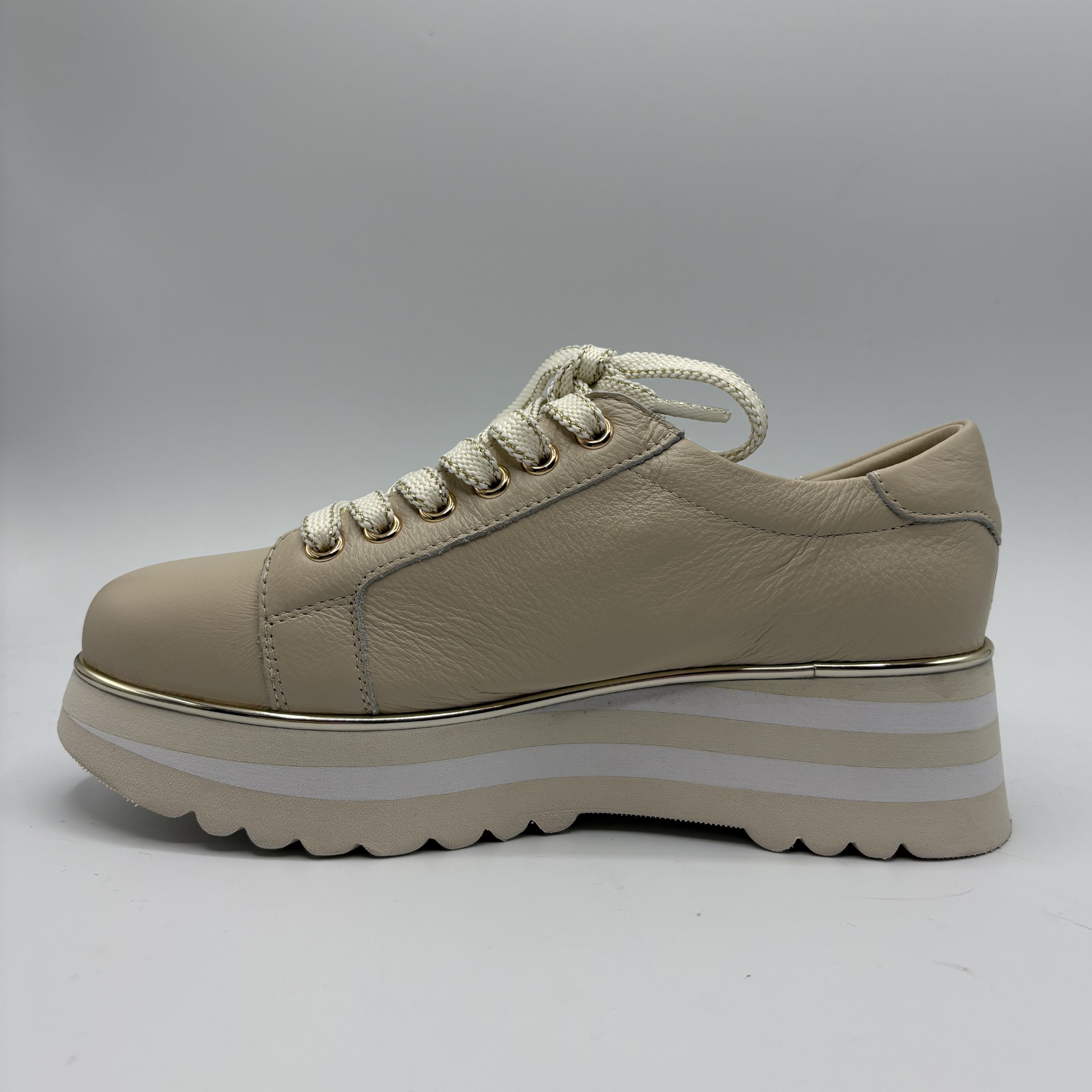 Beige sneaker with a white sole on a gray background