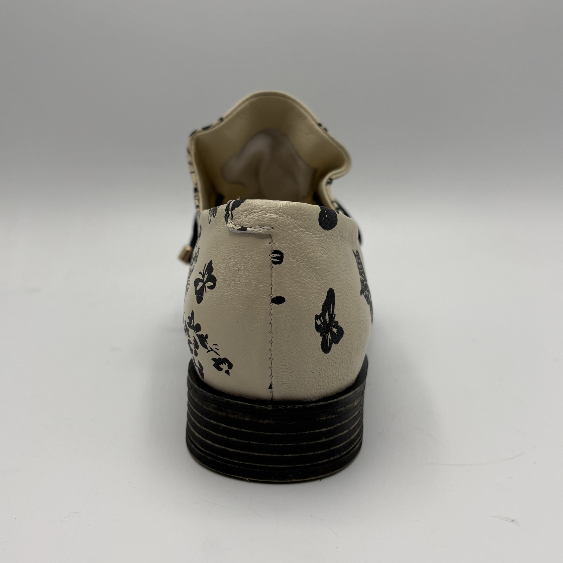 Beige shoe with black floral patterns on a white background