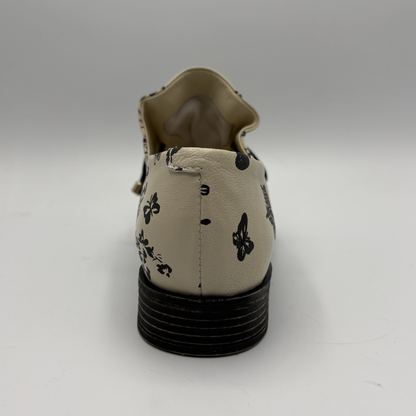 Beige shoe with black floral patterns on a white background