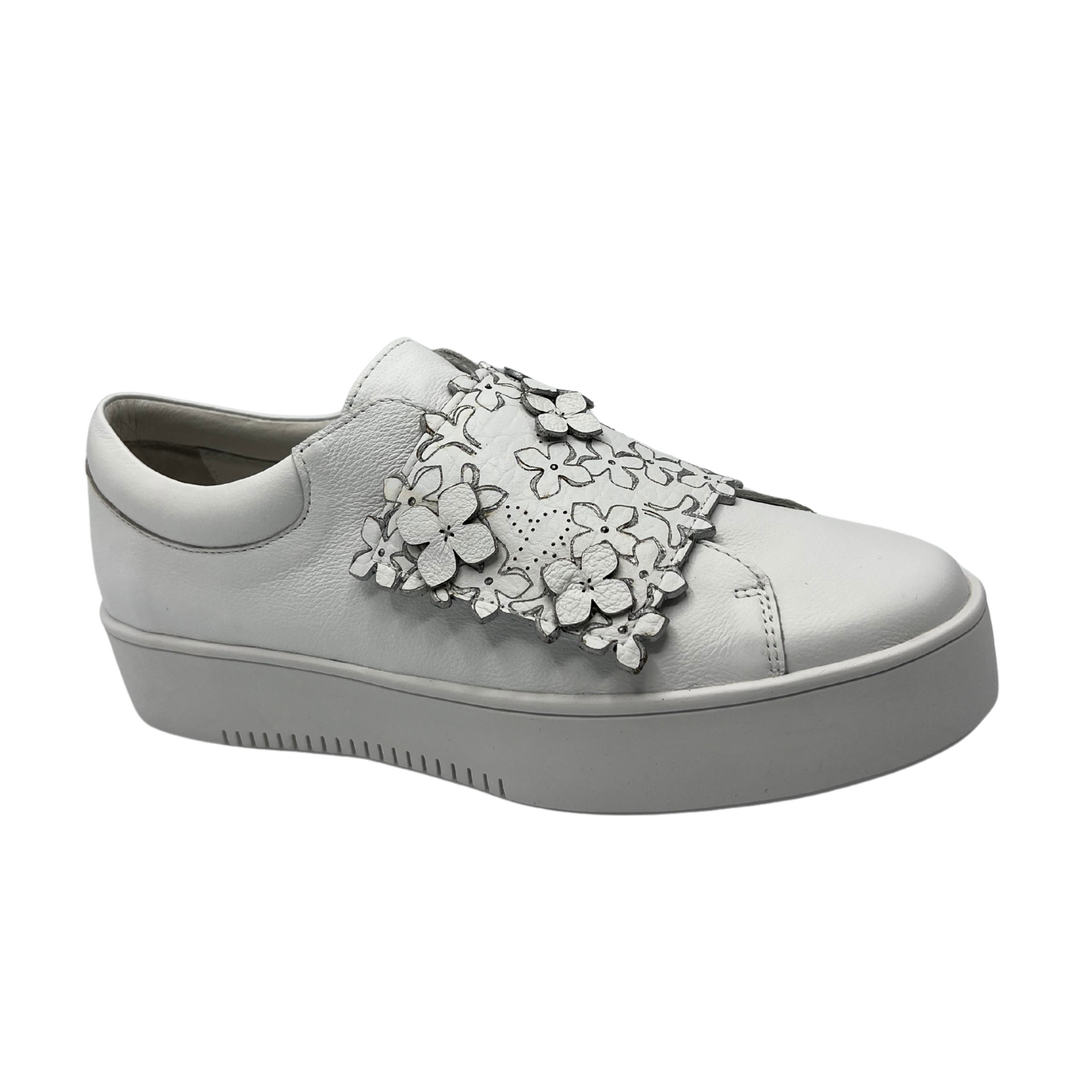 Angled view of white leather sneaker with a 4.5cm platform sole and floral details on the large velcro strap.