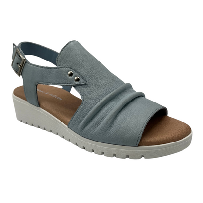 45 degree angled view of light blue leather sandal with buckle strap and white wedge heel