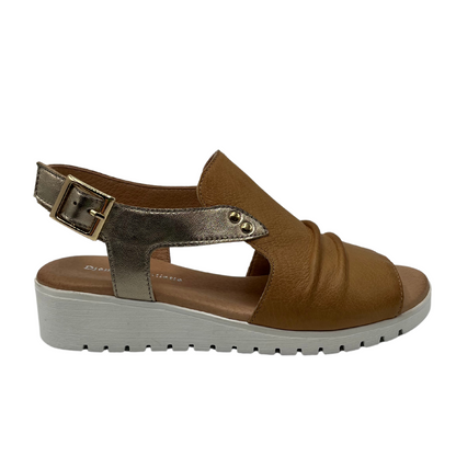 Right facing view of brown leather sandal with gold slingback strap and white wedge heel