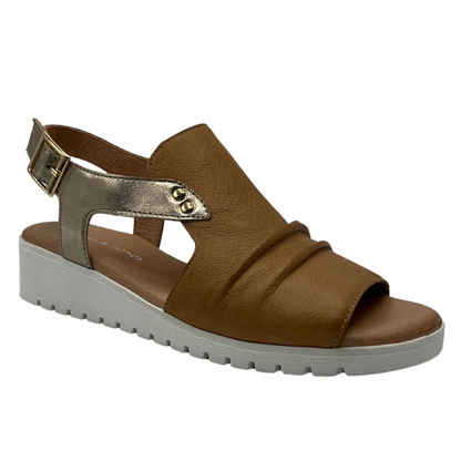 45 degree angled view of brown leather sandal with open toe and sling back strap. Low white wedge heel