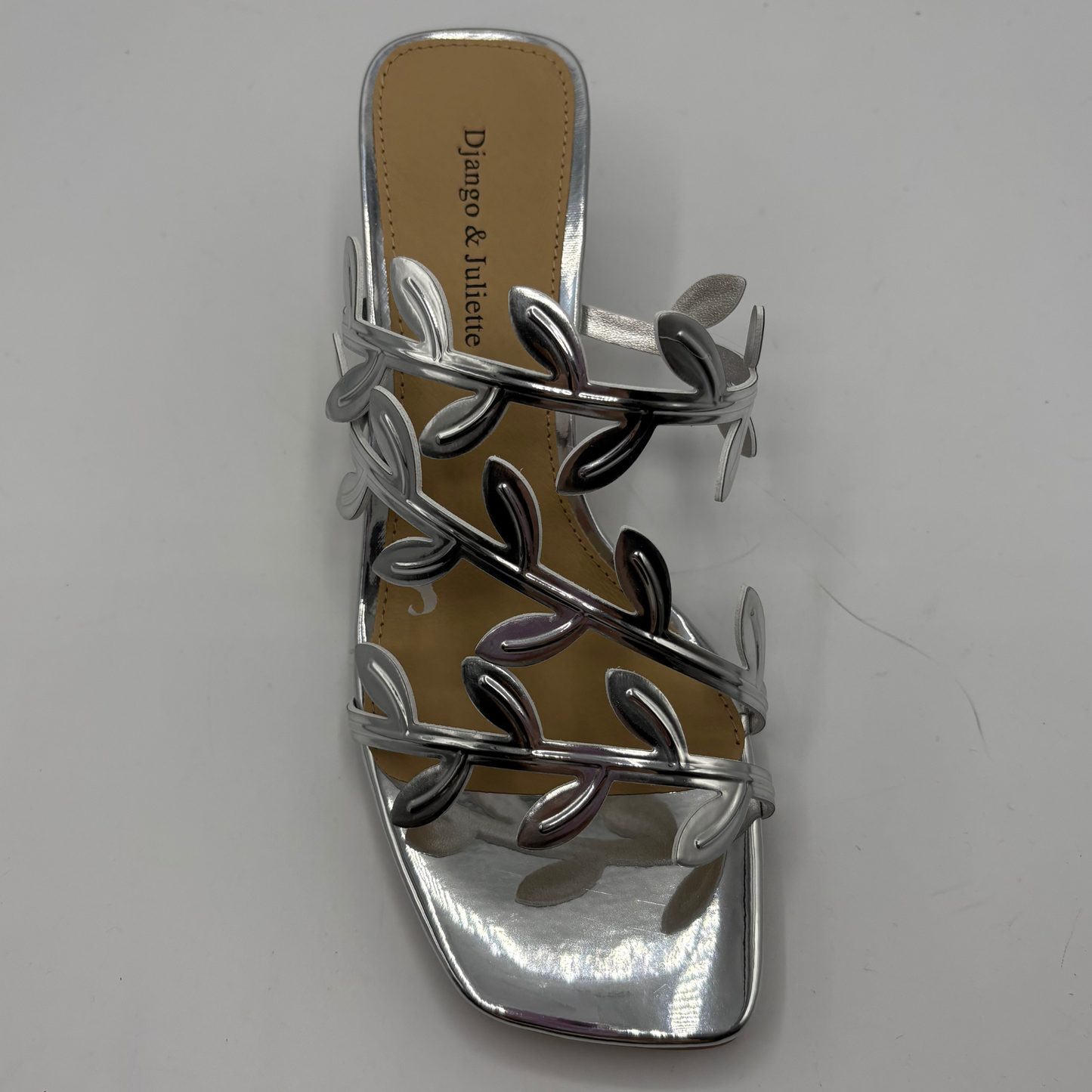 Silver sandal with leaf design on a gray background