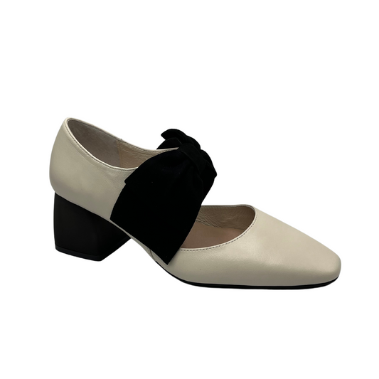 45 degree angled view of cream leather pump with black suede accent bow and short block heel
