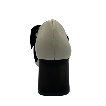 Back view of cream leather pump with black suede accent bow and short block heel
