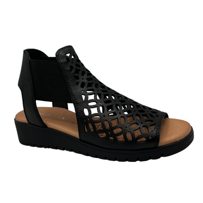 Angled view view of leather die cut wedge sandal in black. Low wedge heel, elasticized sides and open toe 