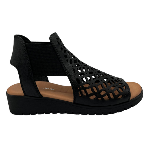 Right facing view of leather die cut wedge sandal in black. Low wedge heel, elasticized sides and open toe 