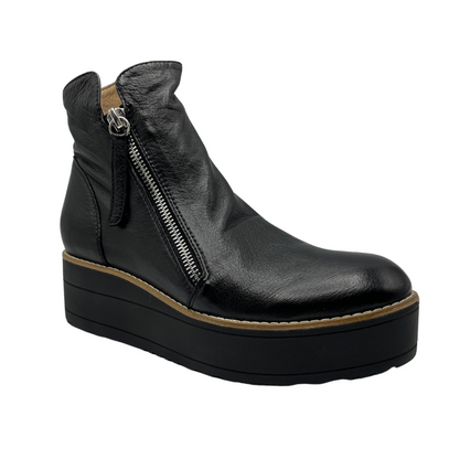 45 degree angled view of black leather short boot with black platform sole and double side zipper closures