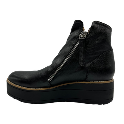 Left facing view of black leather short boot with black platform sole and double side zipper closures