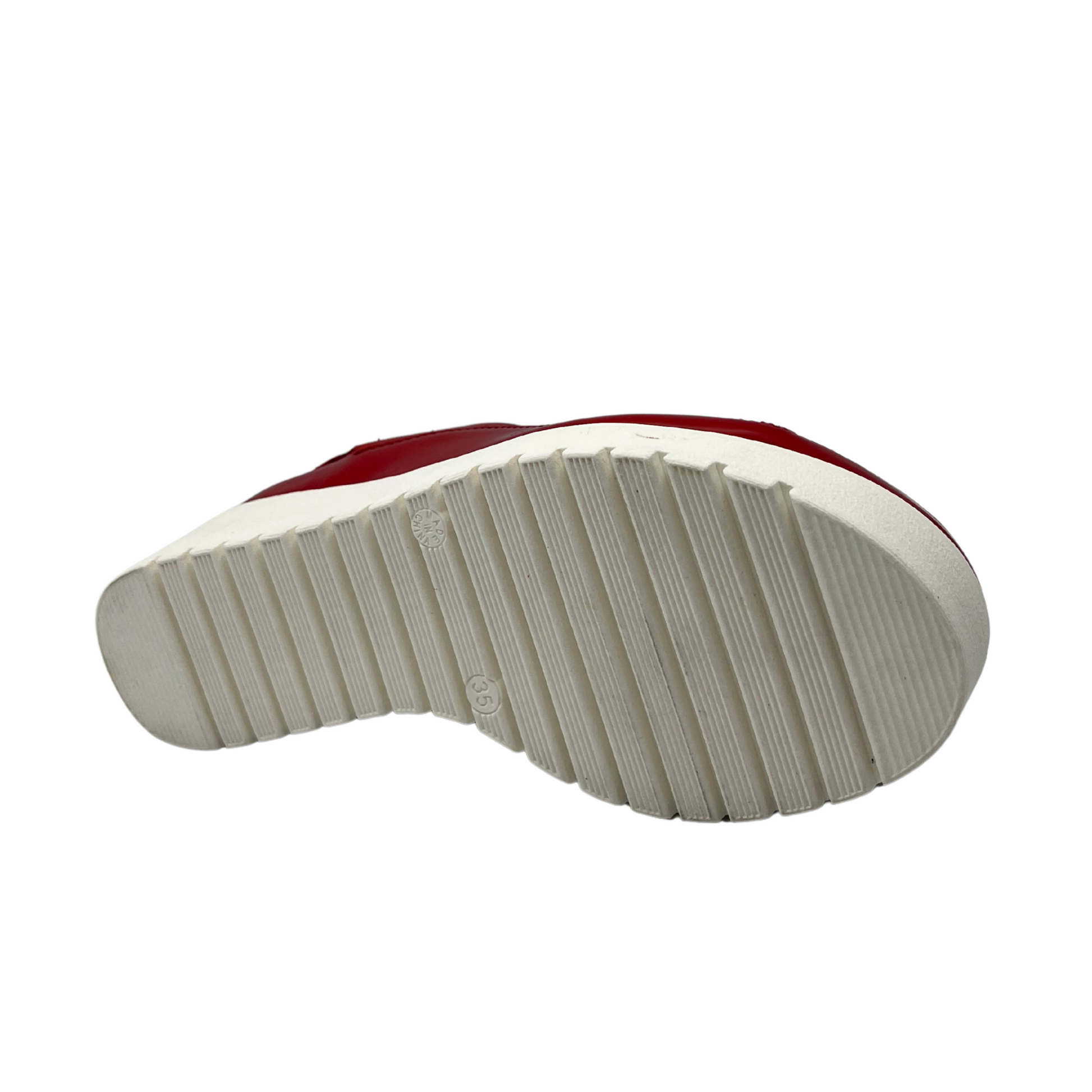 Bottom view of red leather sandal with white rubber outsole. Velcro slingback strap and rounded toe.