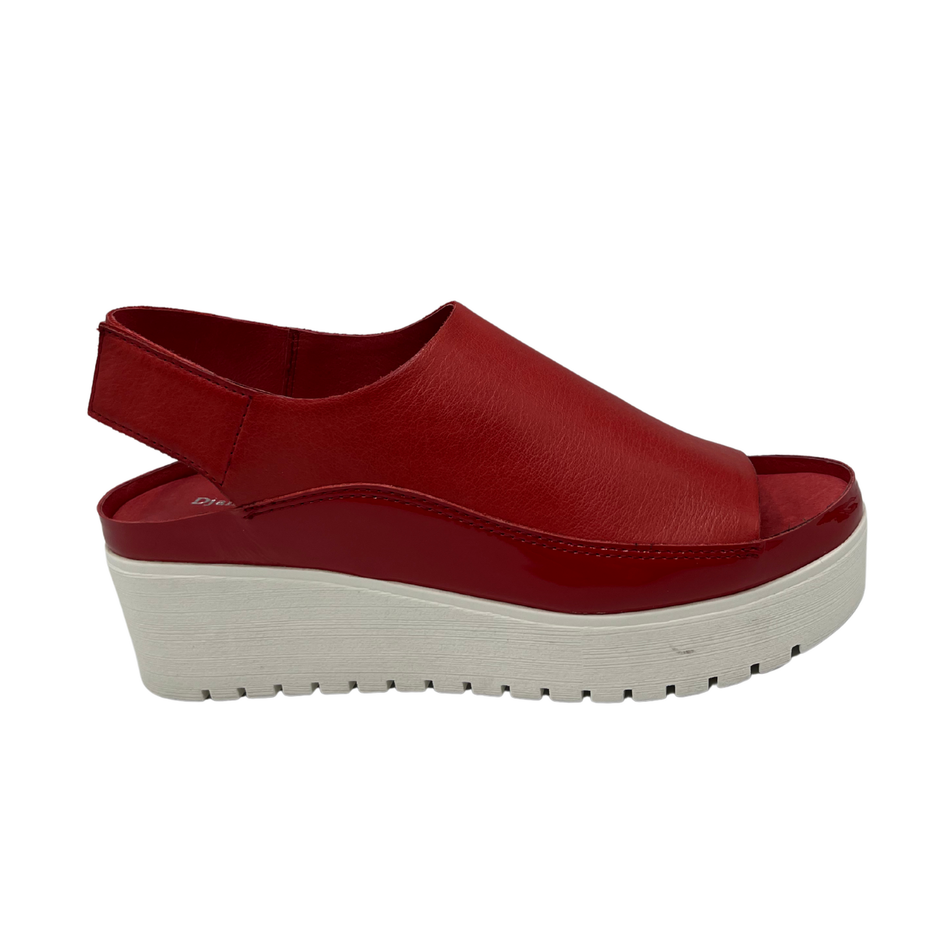 Right facing view of red leather sandal with white rubber outsole. Velcro slingback strap and rounded toe.