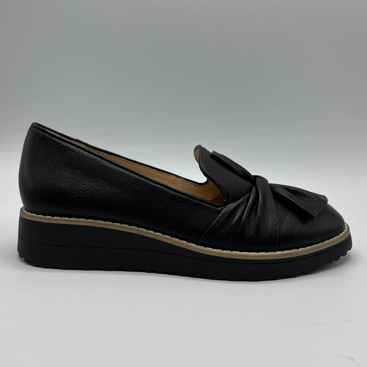 Black loafer shoe with a knot detail on a gray background