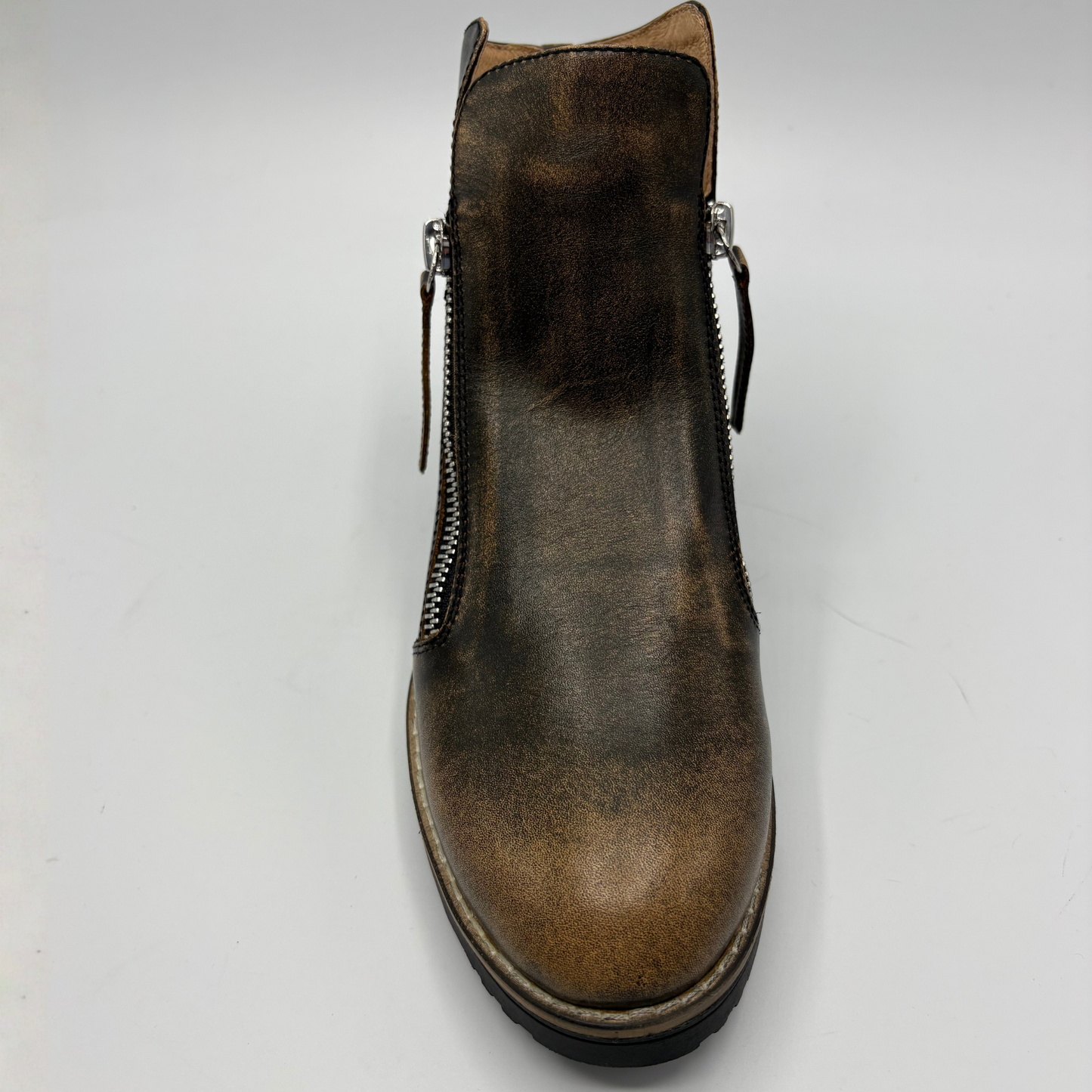 A single brown leather ankle boot with side zippers, shown from a top-down angle on a light gray background.