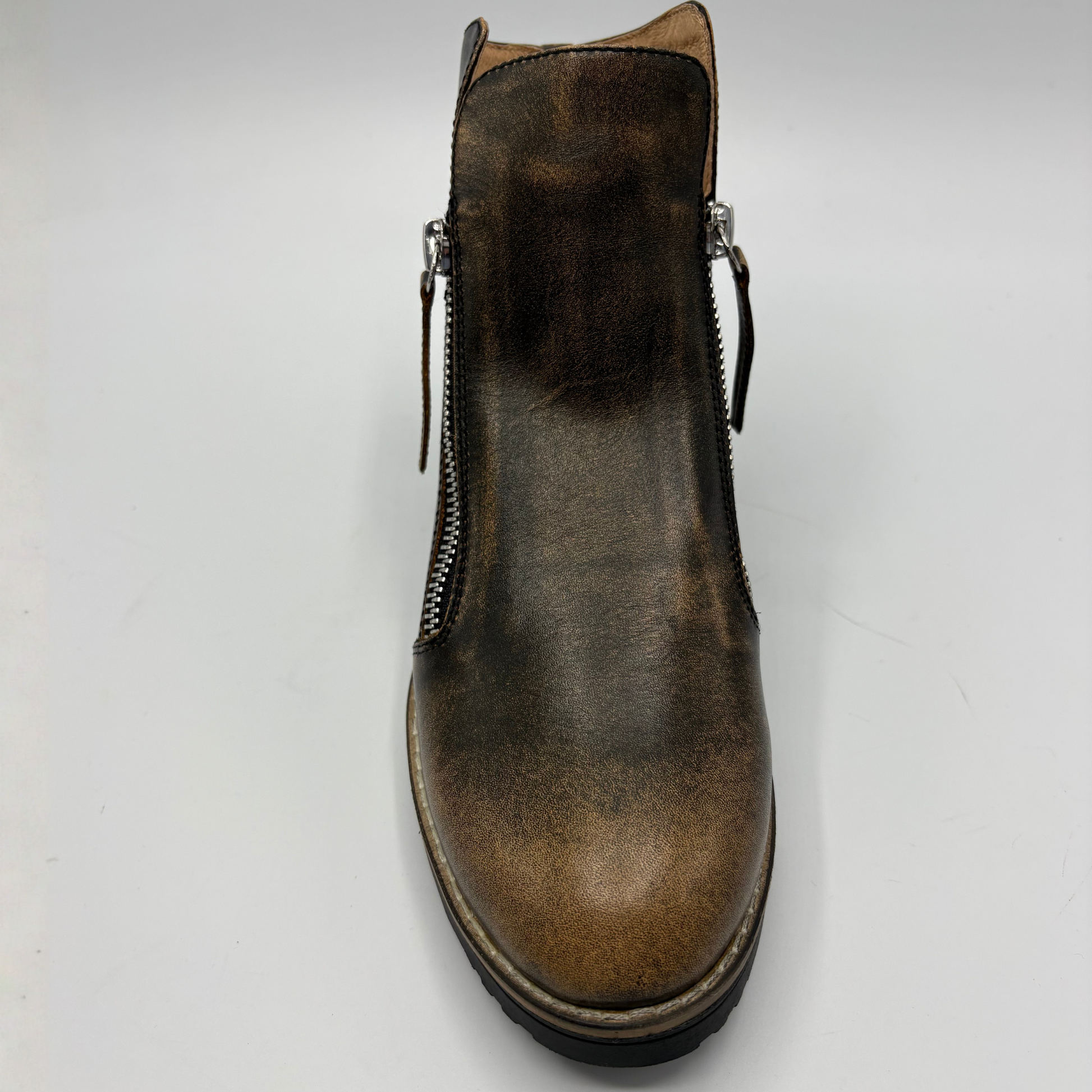 A single brown leather ankle boot with side zippers, shown from a top-down angle on a light gray background.