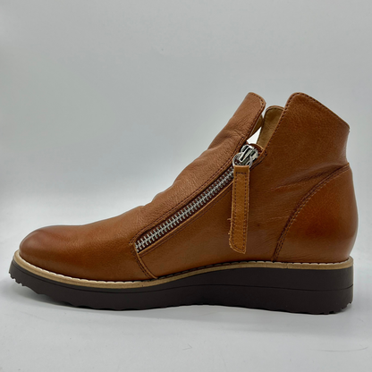 Brown leather ankle boot with a zipper on a gray background
